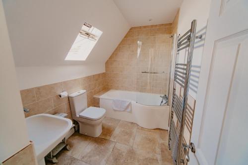 a bathroom with a tub and a toilet and a sink at Dairyman's Cottage At Tapnell Farm in Yarmouth