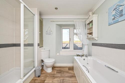 a bathroom with a toilet and a tub and a sink at Polean Farm Old Farmhouse - With Large Jacuzzi, Games Room, Near the Sea and with Free Access to a Nearby Pool in Looe