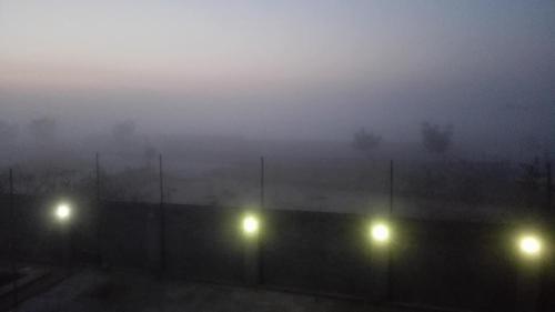 a foggy view of a fence with lights in the fog at Villa Mostafa Sadek, Swimming pool, Tennis & Squash - Borg ElArab Airport Alexandria in Borg El Arab