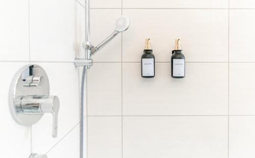 a shower with two bottles on a white tiled wall at Barrierefrei I free parking I Terasse I Netflix in Quedlinburg