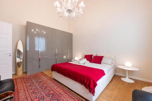 a bedroom with a bed with red sheets and a chandelier at Chic Elegance at Borgo Tommasini Apartment in Parma