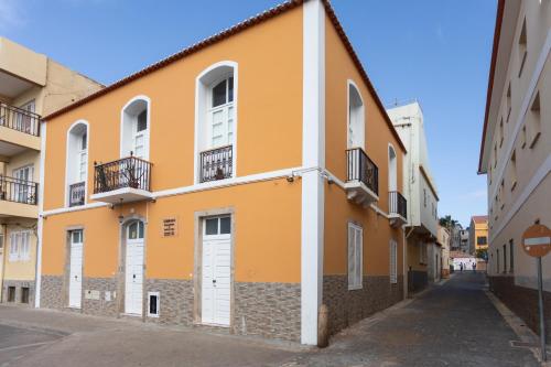 a yellow building with white doors and a street at O Sobrado Mariazinha & Inácio Lima in Praia