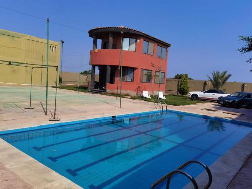 a swimming pool in front of a building at Villa Mostafa Sadek, Swimming pool, Tennis & Squash - Borg ElArab Airport Alexandria in Borg El Arab
