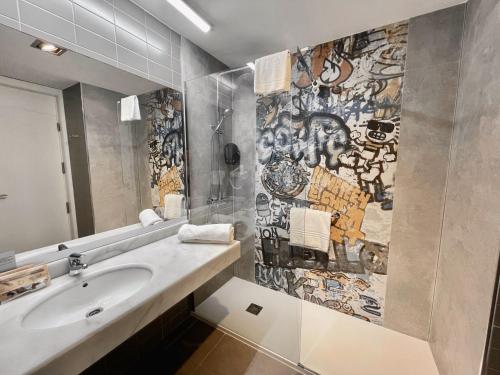 een badkamer met een wastafel en een muur bedekt met graffiti bij Balneario Elgorriaga in Elgorriaga