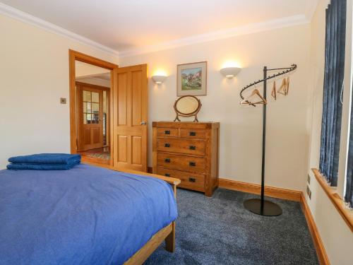 a bedroom with a blue bed and a dresser at Drummygar Mains in Arbroath