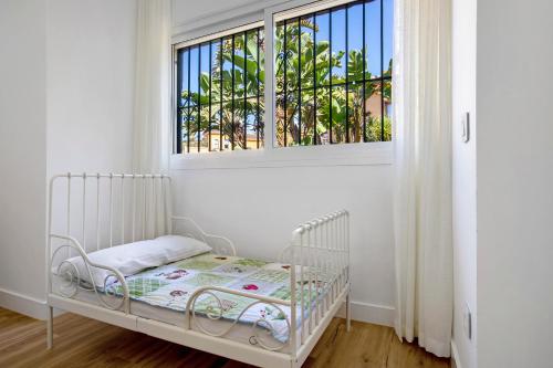 a white crib in a room with a window at Villa For Families los Agaves in La Cala de Mijas