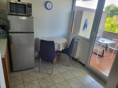 a kitchen with a table and a refrigerator and a table and chairs at F2 möblierte 2,5 Zimmer - Wohnung 60 m2 in Saint-Louis