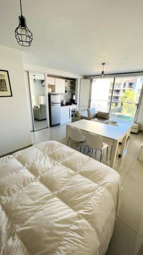 a bedroom with a white bed and a kitchen at Luminoso departamento en Castelar centro p/2 pers in Castelar