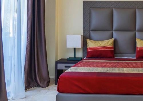 a bedroom with a bed with a red blanket and a lamp at Hôtel Bachou in Dakar