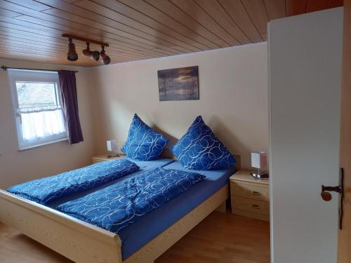 a bedroom with a bed with blue pillows on it at Ferienwohnung In der Kehr in Briedel
