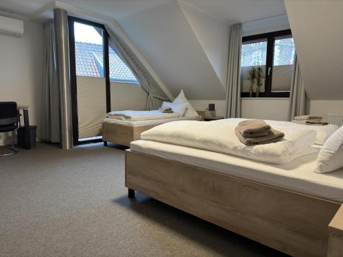 two beds in a room with two windows at Gästehaus am Tiergarten in Raesfeld