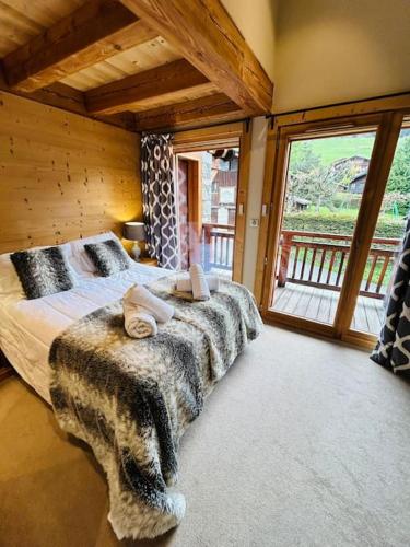 une chambre avec un lit et une grande fenêtre dans l'établissement Chalet Rose, à Morzine