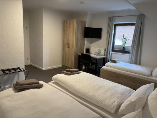 a hotel room with two beds and a desk at Gästehaus am Tiergarten in Raesfeld