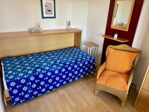 a bedroom with a bed with a blue cover and a chair at Apartement Seeblick in Nordstrand