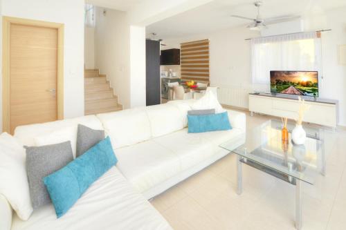 a living room with a white couch and a glass table at Villa Thetida in Ayia Napa