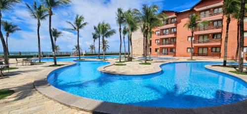a swimming pool in front of a building with palm trees at Blanco Beach Suite Privada, Cumbuco in Cumbuco
