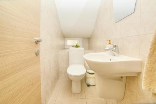 a bathroom with a white toilet and a sink at Villa Thetida in Ayia Napa
