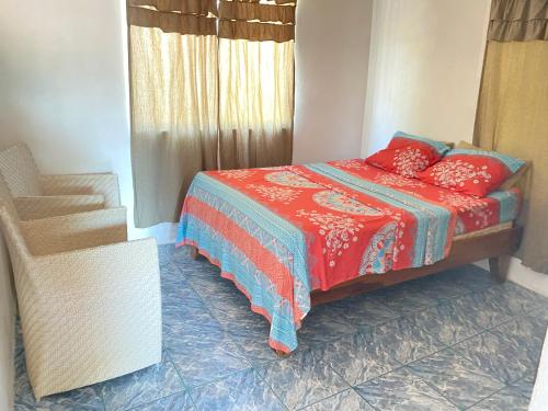 Un dormitorio con una cama con almohadas rojas y una silla en Apartamento Tamar en Quepos