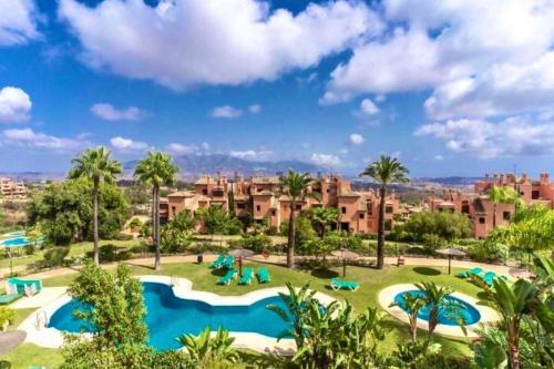 een uitzicht op een resort met 2 zwembaden en palmbomen bij El Mirador del Golf Marbella 3 bedroom apartment in Ojén