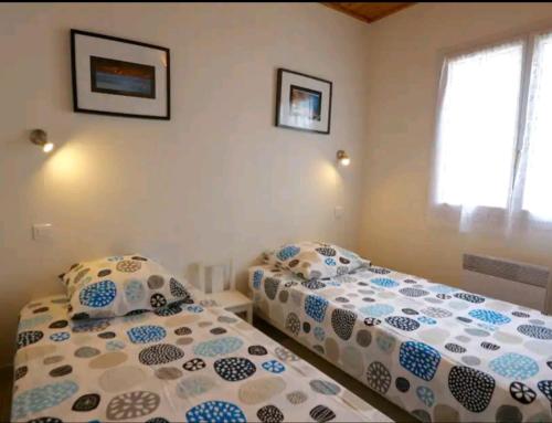 ブルティニョール・シュル・メールにあるMaison a 150 m de la plage de Bretignolles sur merのベッドが2つと窓が2つある寝室