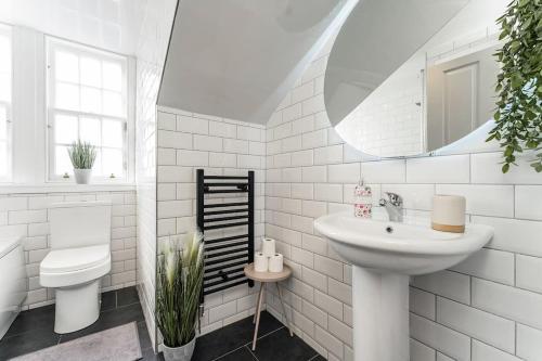 Baño blanco con lavabo y espejo en The Glasgow Rose- Stylish Penthouse 2 Bed City Centre Apartment with Free Parking & Lift en Glasgow