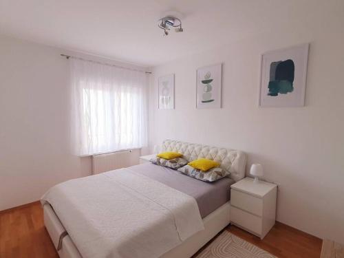 a white bedroom with a large bed with yellow pillows at Apartment Felix in Rijeka