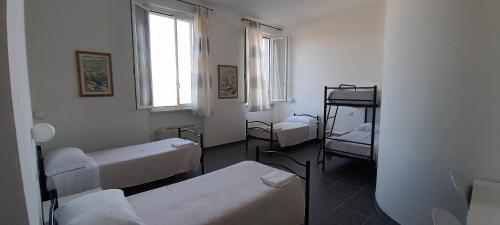a room with three beds and a window at Il Pescemagra HostelAmeglia in Ameglia