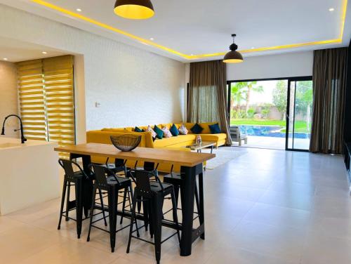 sala de estar con mesa y sofá amarillo en Villa Khmissa 5, en Marrakech