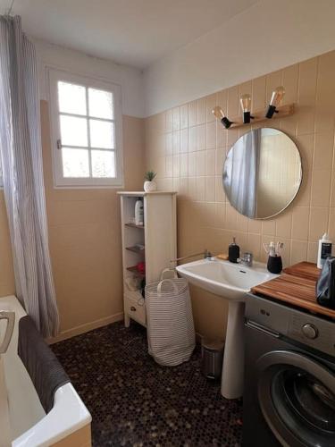 une salle de bain avec un lavabo et un miroir et une machine à laver dans l'établissement Agréable Maison Landaise proche du Lac, à Sanguinet