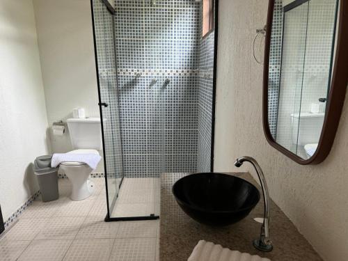 uma casa de banho com uma cabina de duche em vidro e uma banheira preta. em Chalé 10 até 4 pessoas cozinha próx ao centro em Itatiaia