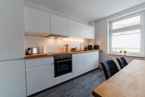cocina con armarios blancos y mesa de madera en Luxury Vista Apartment I Küche I WLAN I Smart-TV, en Magdeburgo