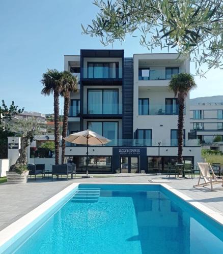 un hôtel avec une piscine en face d'un bâtiment dans l'établissement Božikovina Beach Rooms, à Podstrana