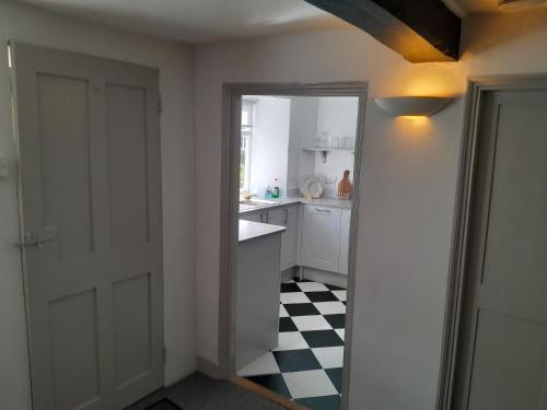 uma cozinha branca com piso em xadrez preto e branco em Mews Cottage, a 2 bedroom Georgian Cottage which comfortably sleeps 4 located in a quiet courtyard in the centre of Olney em Olney