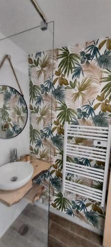 un bagno con un lavandino e una parete con palme di Chambres d'hôtes Un Eté Sans Fin à 50 m de la plage à Canet plage a Canet-en-Roussillon