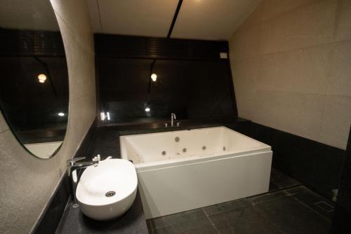 a bathroom with a tub and a toilet and a sink at Bliss Nirvana Resort in Lonavala