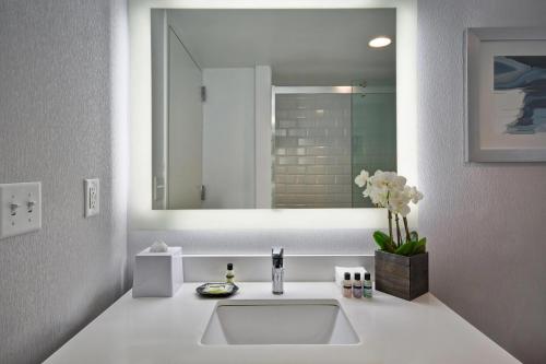 Baño blanco con lavabo y espejo en Four Points by Sheraton Boston Newton, en Newton
