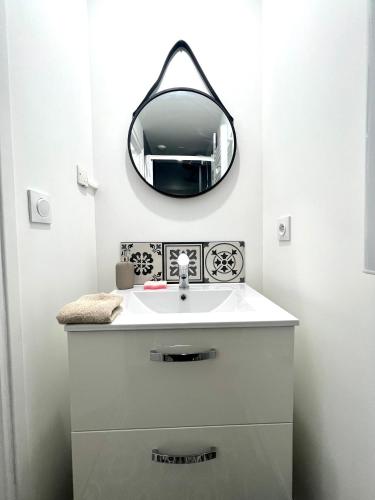 une salle de bain avec un lavabo et un miroir au mur dans l'établissement Place St Epvre - Cosy studio rénové, à Nancy