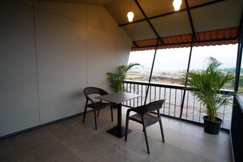 a table and chairs in a room with a balcony at Bliss Nirvana Resort in Lonavala