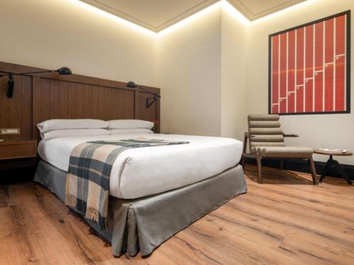 a bedroom with a large bed and a chair at Only YOU Hotel Atocha in Madrid