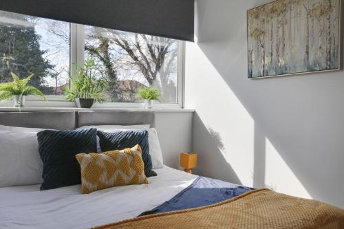 a bedroom with a bed and a window with plants at Niche Sunrise Townhouse in Chelmsford