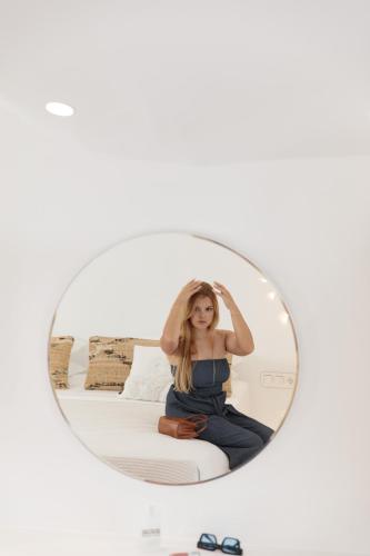 a woman sitting on a bed in a mirror at Naxos Cave Suites in Stelida