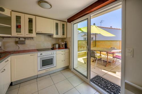 une cuisine avec des armoires blanches et une table avec vue sur un patio dans l'établissement Arcachon Balsamo plage 8, à Arcachon