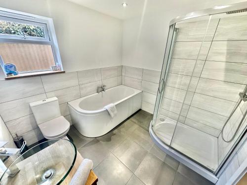 a bathroom with a tub and a toilet and a shower at Stylish Coastal Retreat with Garden, Hot Tub and Gas BBQ in Bournemouth