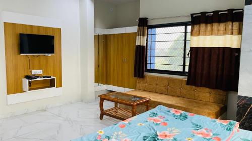 uma sala de estar com uma cama e uma televisão em Hotel Anmol Resort em Indore