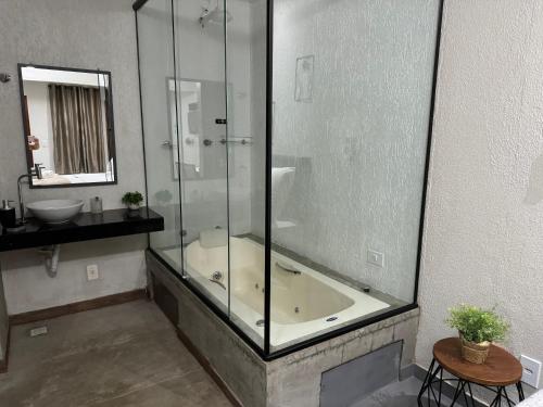 uma casa de banho com um chuveiro, uma banheira e um lavatório. em Chalé 01 com hidro e cozinha no coração de Penedo em Itatiaia