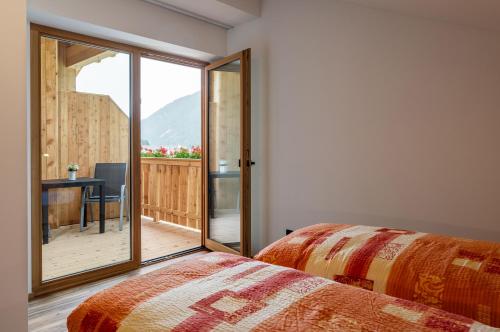 a bedroom with a bed and a view of a balcony at Kahnwirt in Valle Di Casies