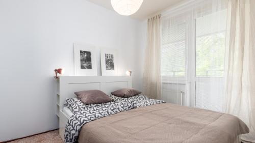 a white bedroom with a bed and a window at UrbanElegance Escape, top location, private parking in Bratislava