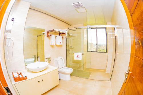 a bathroom with a shower and a toilet and a sink at M Hotel Kigali in Kigali