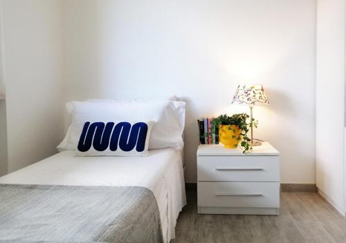 a bedroom with a white bed and a night stand with a lamp at HoliHome_Casa di Sara in Tortoreto Lido