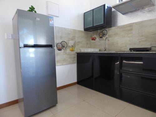 a stainless steel refrigerator in a kitchen with black cabinets at La Nuit Étoilée in La Gaulette